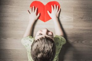 תמונת ילד קטן מביט למעלה ומחזיק ציור של לב אדום- מתוך פוסט בנושא ילדים פוגעים באתר של מאור קפלן- מובילה תהליכי חינוך מיני במרחב הדתי